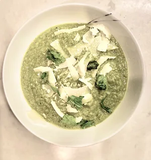 a mini-bowl of a bite-sized soup with cheese flakes on top