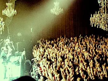 Side view of crowd at small concert venue with band on stage