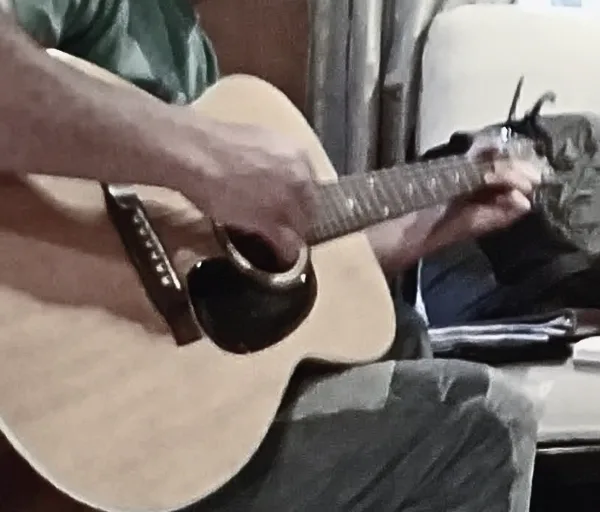 The torso of a person strumming on a guitar