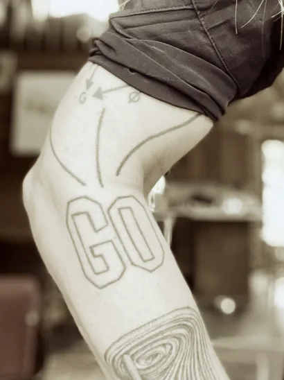 Photo of a tattoo on a forearm that is the word GO in capital letters.