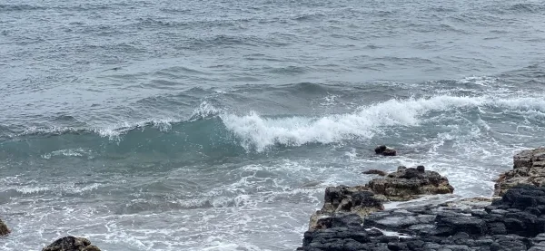 ocean waves cresting with rock formations in foreground