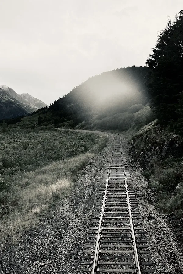 One set of train tracks heading straight forward then curving left.