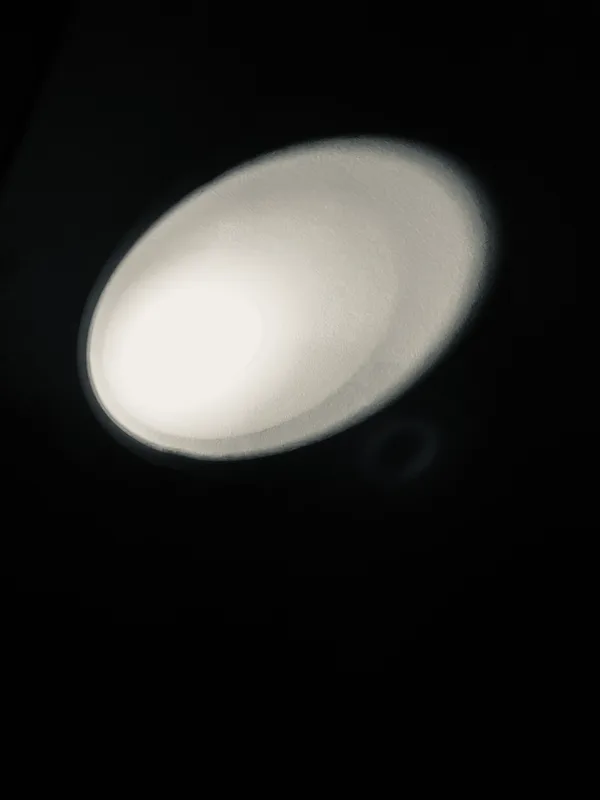 Flashlight beam on a wall in the shape of an ellipse.