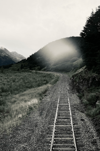 One set of train tracks heading straight forward then curving left.
