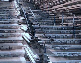 a wide staircase made up of wood and stone steps that are in parallel and three banisters that are in parallel.
